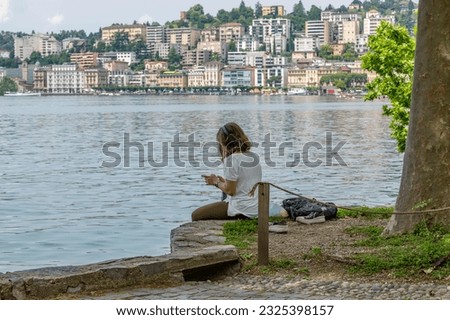A woman relaxes in Ciani Park in Lugano, Switzerland, listening to music on headphones Royalty-Free Stock Photo #2325398157