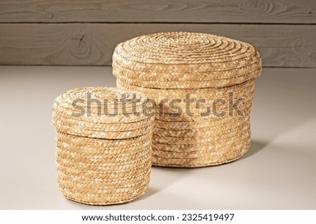 Two baskets - large and small, woven from rattan, for storing household items on a wooden background.