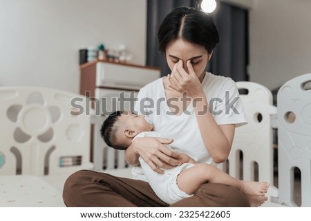 Tired Asian mother suffering from experiencing postnatal depression. Healthcare single mom motherhood stressful. Royalty-Free Stock Photo #2325422605
