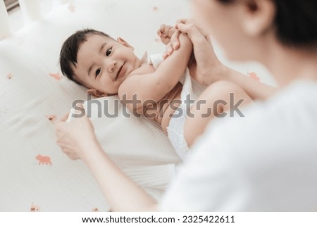 Top view mother wearing clothes to her baby. Asian family mother’s day. Baby healthcare hygiene concept. Royalty-Free Stock Photo #2325422611