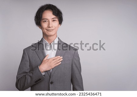 Business person portrait. A man in a gray jacket is gesturing. hand on chest. Royalty-Free Stock Photo #2325436471