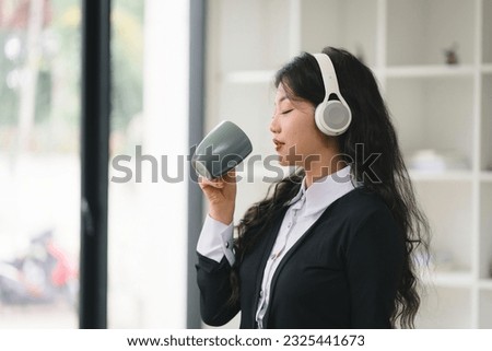 Portrait of a young asian woman enjoy drinking coffee and listening to music with headphone