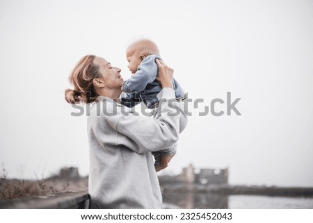 Tender woman caressing her little baby boy infant child outdoors on autumn trip to Secovlje salinas landscape park, Slovenia. Mother's unconditional love for her child