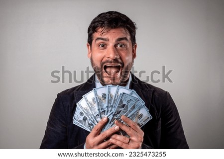 Happy man with many dollars in his hands. Surprised man showing many dollar bills. Business man making a lot of money. Person holding dollar bills. copy space