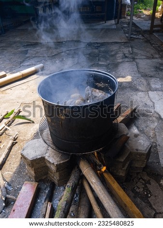 cooking beef with traditional cookware using firewood in the yard Royalty-Free Stock Photo #2325480825