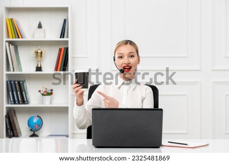 customer service cute blonde girl office shirt with headset and computer pointing at coffee cup