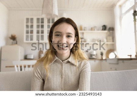 Cheerful pretty young school kid teenage girl talking on video call, chatting online, enjoying conversation, Internet communication, looking at camera with toothy smile. Home head shot portrait
