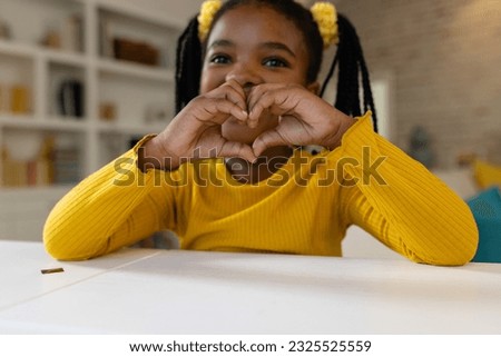 Happy african american girl making video call at home. Lifestyle, communication, childhood and domestic life, unaltered.