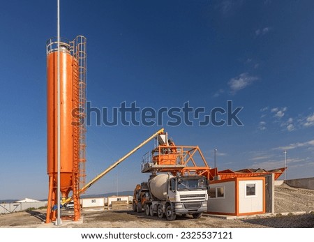 Cement mixing plant and mixer truck. Concrete factory concept Royalty-Free Stock Photo #2325537121