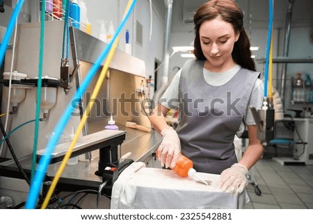 Dry-cleaning operator adding solvent to spots, treating clothes before cleaning Royalty-Free Stock Photo #2325542881