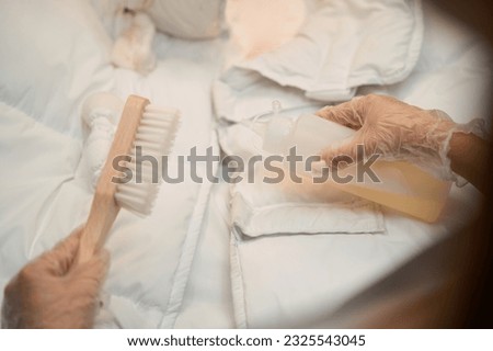 Close-up female hands in protective gloves applying solvent on dirt at jacket Royalty-Free Stock Photo #2325543045
