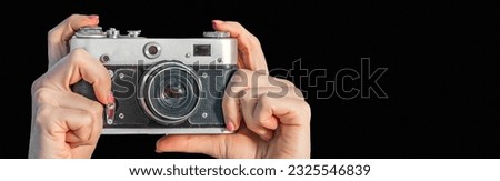 Retro camera in female hands close-up. Woman hands holding photo camera isolated on black background. Banner design