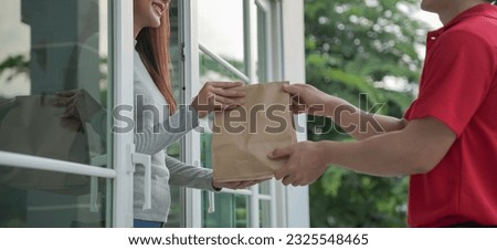 Happy smiling Asian woman receives paper bag parcel of food from courier front house. Delivery man send deliver express. online shopping, paper container, takeaway, postman, delivery service, packages Royalty-Free Stock Photo #2325548465