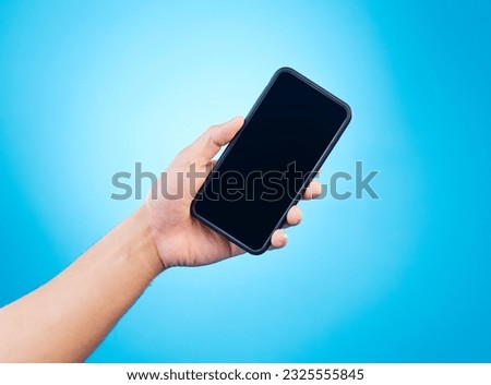 Mockup, blue background and hand with phone in studio for mobile app, website and social media. Advertising, marketing and isolated person holding smartphone for promotion, branding and information