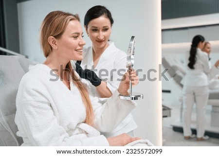 Woman examines her face after undergoing anti-aging procedures Royalty-Free Stock Photo #2325572099
