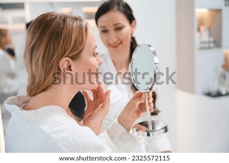 Brunette cosmetologist consults a blonde client in a cosmetology clinic Royalty-Free Stock Photo #2325572115