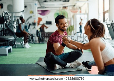 Happy athlete and his female friend supporting each other while exercising in a gym.  Royalty-Free Stock Photo #2325600793