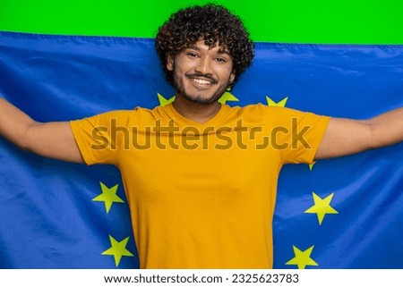 Happy young indian man waving European Union flag, smiling, cheering democratic laws, human rights, freedoms in Europe. Vote, president election. Hindu guy isolated on green chroma key background