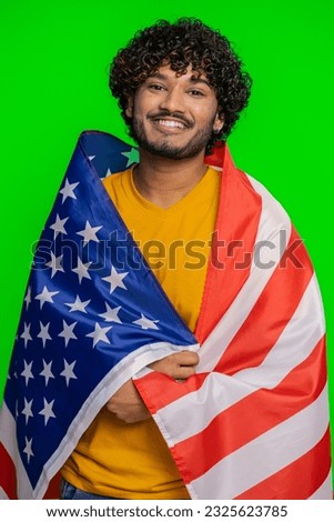 Young indian man waving and wrapping in American USA flag, celebrating, human rights and freedoms. Vote, president election. Independence day. Hindu guy patriot isolated on green chroma key background
