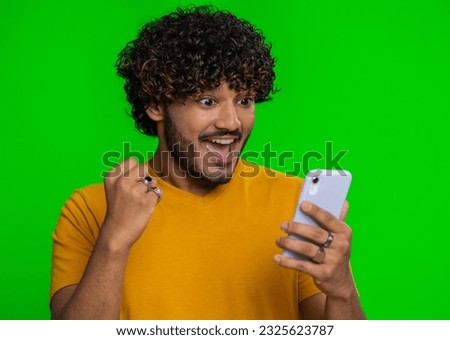 Happy excited joyful indian man in green shirt use smartphone typing browsing shouting say wow yes found out great big win, good news, lottery goal achievemen, celebrating success, winning game
