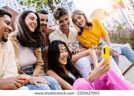 Young group of gen z people having fun using cell phone together outside. Cheerful community of student zoomers enjoying social media content on smartphone app. Royalty-Free Stock Photo #2325627093