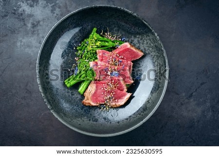 Modern style baby broccoli with fried dry aged sliced beef fillet steak served as top view on a Nordic design plate  Royalty-Free Stock Photo #2325630595