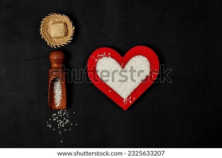 wooden flour spoon with granulated tapioca flour and hollowed out red heart with granulated tapioca flour inside, isolated black background with selective focus