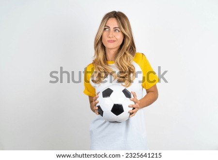 Young beautiful woman holding football ball over white background steepled fingers and looks mysterious aside has great evil plan in mind