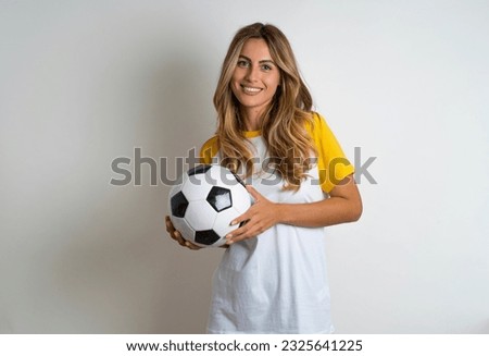 Pleased Young beautiful woman holding football ball over white background keeps hands crossed over chest looks happily aside