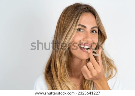 Young beautiful caucasian woman over white background holding an invisible aligner ready to use it. Dental healthcare and confidence concept. Royalty-Free Stock Photo #2325641227