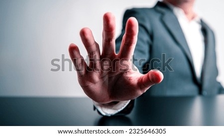 Businessman raising hand in front of prohibiting or stopping forbid and invalid gesture sign on black table and white background. Corruption warning and illegal concept. Anti-corruption and restrain. Royalty-Free Stock Photo #2325646305