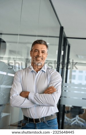Happy confident mature business man standing in office arms crossed, portrait. Smiling mid aged businessman company manager, successful older professional executive looking at camera, portrait.
