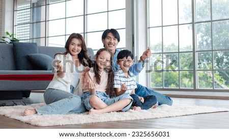 Asian happy cheerful joyful family husband and wife lover couple sitting on carpet floor with little boy son and girl daughter in living room.
