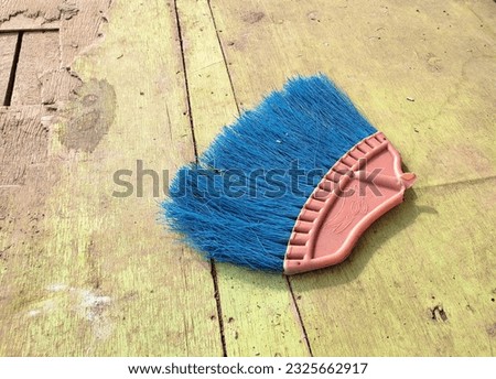 a broken blue floor broom lies on a wooden plank