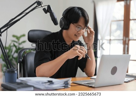 Male podcaster use laptop and speaking on microphone to recording audio podcast in broadcast studio.