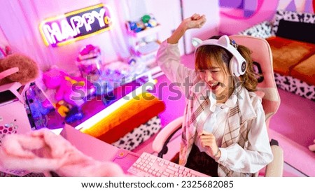 Young Asian woman esport player playing online game on computer in bedroom. Attractive girl vlogger influencer gamer enjoy and fun live streaming broadcast games challenge on social media platform.