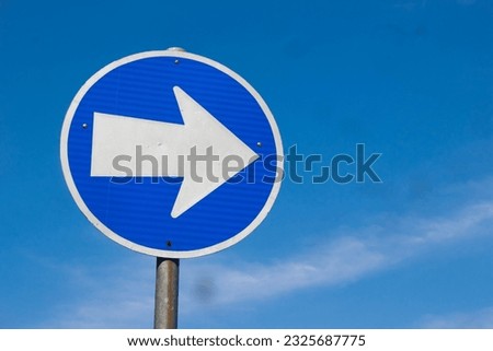 Blue road sign pointing direction on a light background