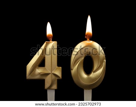 Burning gold birthday candles isolated on black background. Number 40.