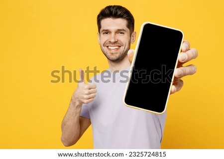 Young man wear light purple t-shirt casual clothes hold in hand use close up mobile cell phone with blank screen workspace area isolated on plain yellow background studio portrait. Lifestyle concept