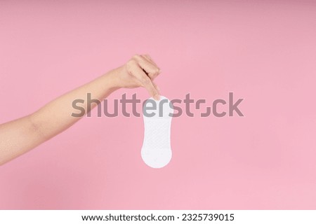 Pantyliner in the hands of the girl on a pink background.