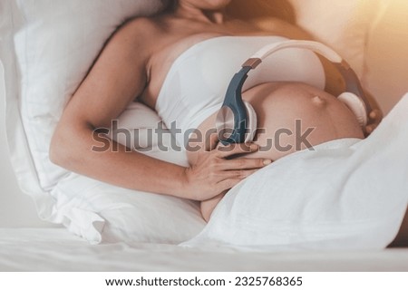 Prenatal care and pregnancy concepts of motherhood. Pregnant women play classical music for fetal headphones in order to treat and care for the mental health of the baby in the womb. Royalty-Free Stock Photo #2325768365