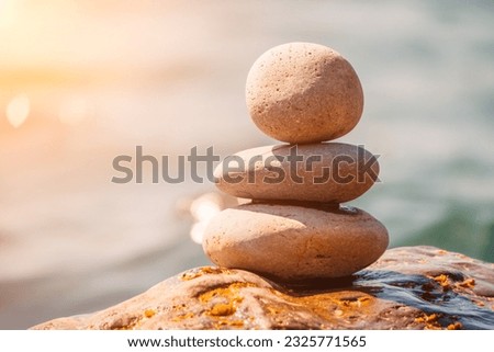 Pyramid stones on the seashore on a sunny day on the blue sea background. Happy holidays. Pebble beach, calm sea, travel destination. Concept of happy vacation on the sea, meditation, spa, calmness.