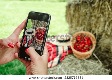Woman taking picture on her Phone of basket with strawberries