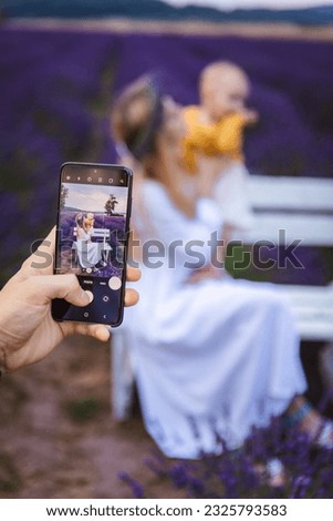 A man takes a picture of his wife and child using his smartphone as he is taking the picture