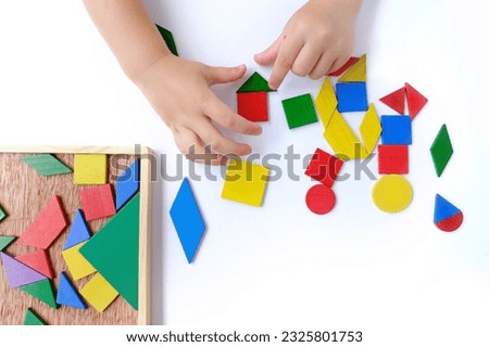 children's hands create pictures from colored wooden geometric shapes, little child, girl 3 years old playing with educational toy, concept children's imagination, unique works art, finished artworks