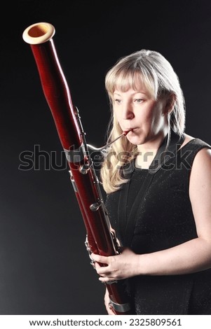 Bassoon woodwind instrument player. Classical musician woman playing orchestral bass. Wind instrument Royalty-Free Stock Photo #2325809561