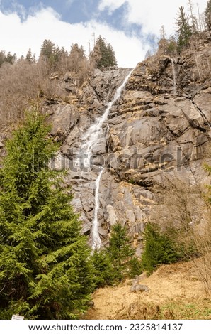 Waterfall in Italian alps. Spring photo with little water and some snow and ice.