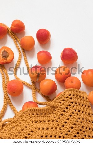 Crochet yellow market bag with fresh organic apricots on a white background. Vegetarian food concept. Top view. Copy space.