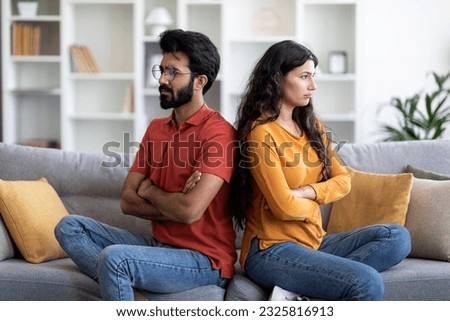 Young Indian Couple Sitting Back To Back On Couch At Home, Upset Eastern Man And Woman Offended After Domestic Quarrel, Suffering Family Conflicts And Problems In Relationship, Free Space Royalty-Free Stock Photo #2325816913