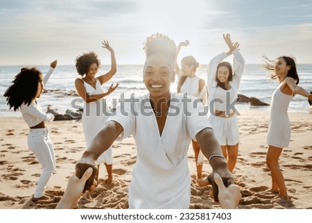 Diverse group of happy young female friends having fun and dancing outdoors on the beach, women celebrating hen party on coastline. Enjoying our beach day together